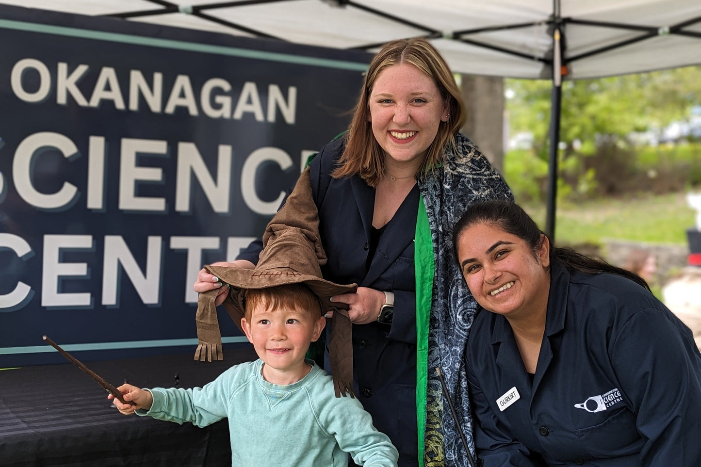 Two young women and a child in front of a sign